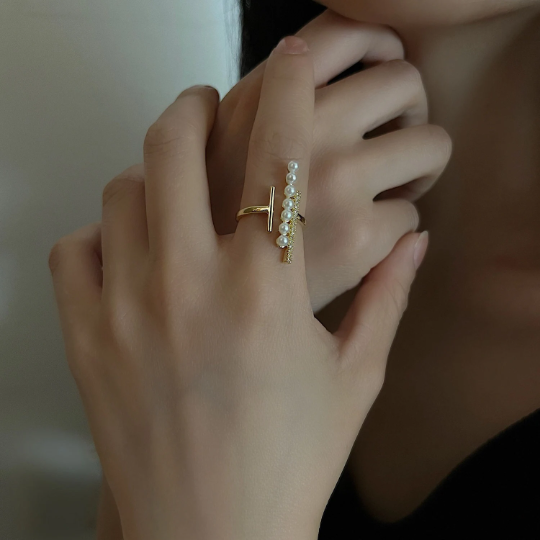 an asymmetrical faux pearl ring on a woman's hand